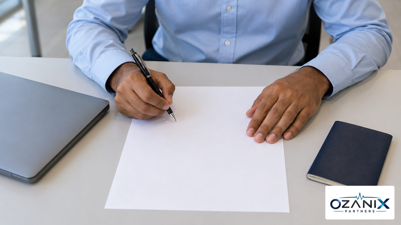 A candidate's hands holding a pen over a blank answer sheet beside a closed laptop and passport before a UAE health licence exam